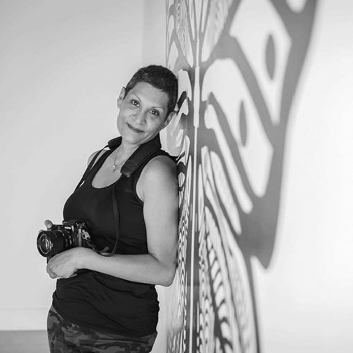 Amina Mohamed holding her camera with a butterfly shadow on the wall